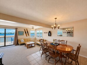 A spacious living area with a large dining table, comfortable seating, and a view of the water. - Waters Edge Lakefront Escape (Gravois Mills)