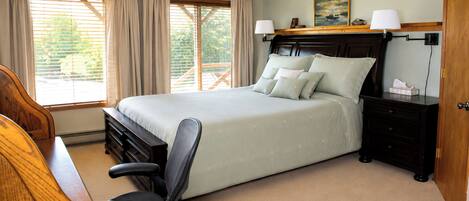 A bedroom with a bed, bedside tables, a chair, a desk, and a window with curtains.