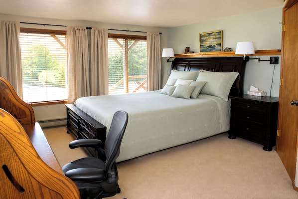 A bedroom with a bed, bedside tables, a chair, a desk, and a window with curtains.