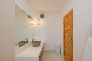 Casa de banho com lavatório duplo, espelho, duas luzes de parede, aquecedor e porta de madeira.