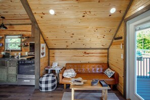 A compact living space with a kitchenette, a sofa, and a dining table. - Communal Fire Pit & Dock! Tiny Home By Lake Murray (Gilbert)