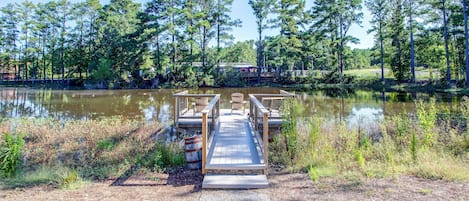 A wooden dock extending into a calm lake surrounded by trees.