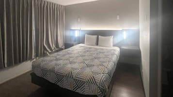 A hotel room with a bed, curtains, and bedside lamps.