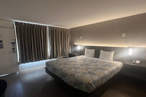 Een moderne hotelkamer met een groot bed, een bureau en een raam met gordijnen.