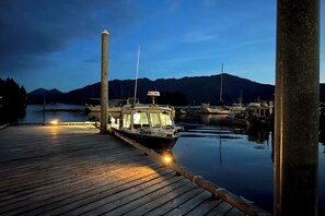 Un vaixell amarrat a la marina, amb aigua tranquil·la i muntanyes al fons.