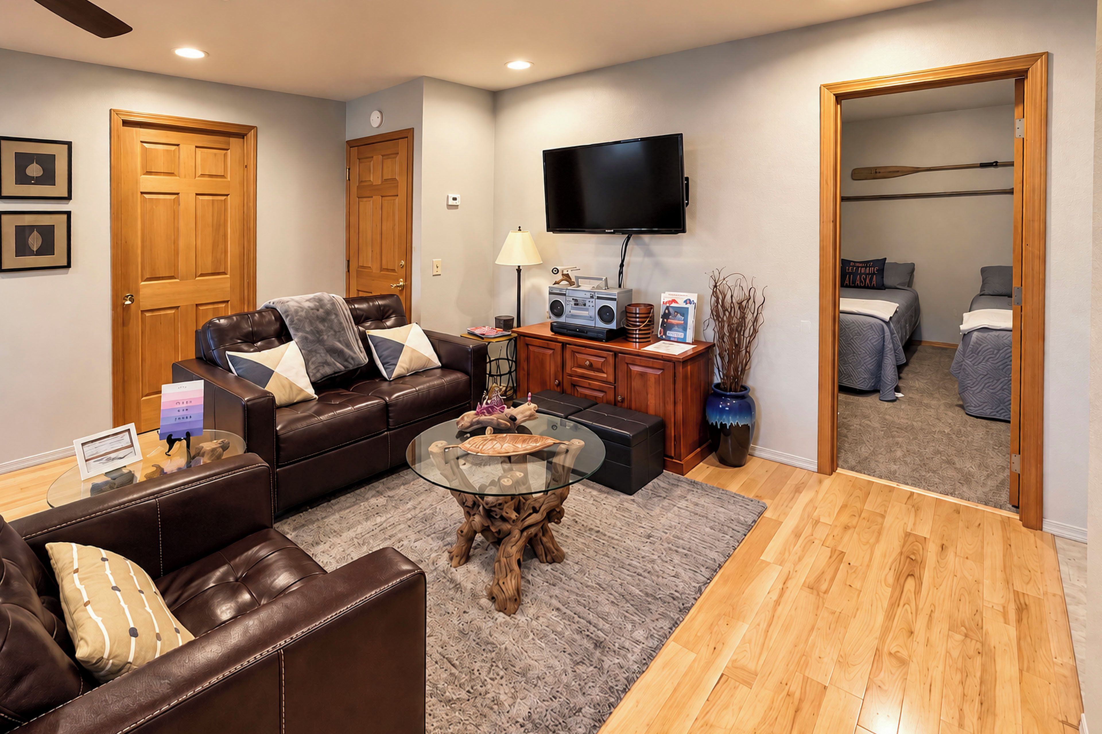 A modern living room with a leather sofa, a glass coffee table, and a flat-screen TV mounted on the wall.