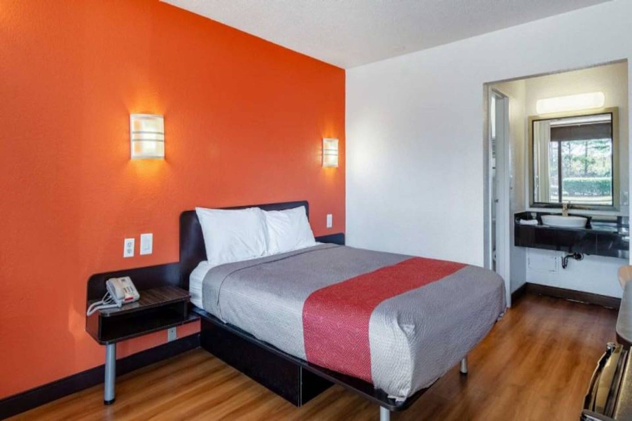 A hotel room with a bed, bedside table, and a window with a view.