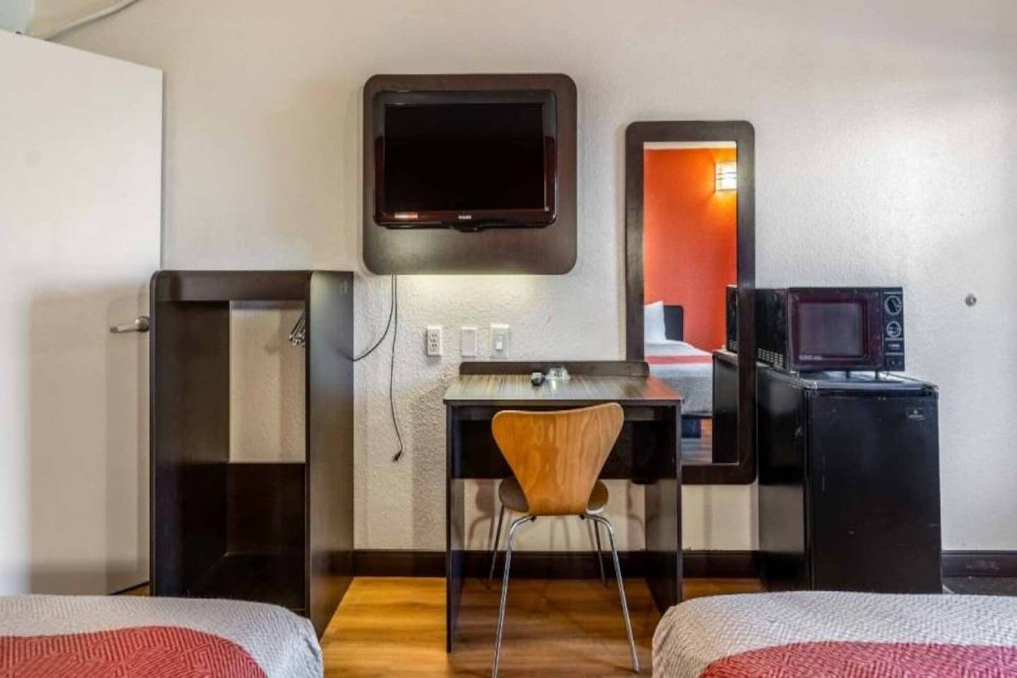 Een hotelkamer met een bed, een bureau, een stoel, een televisie en een magnetron.