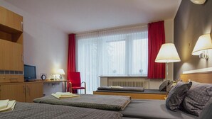 Hotelkamer met twee bedden, een bureau, een stoel, een televisietoestel en een raam met gordijnen.