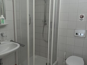 Un baño con ducha, lavabo e inodoro.
