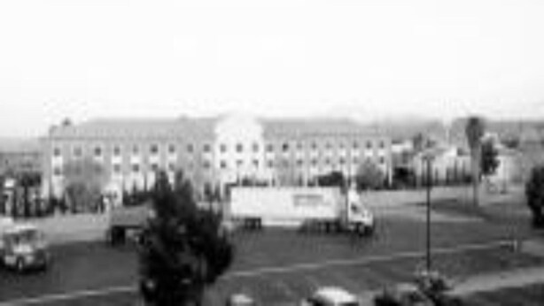 Un edifici gran amb diverses finestres i un pàrquing al davant.