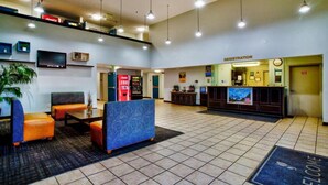 A lobby with seating, a Coca-Cola vending machine, a registration desk, and a television screen. - 2 Queen Beds | Non-Smoking (Hesperia)