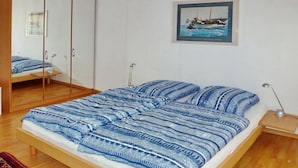 Un dormitorio con cama de madera, un espejo, un cuadro en la pared y una alfombra estampada.