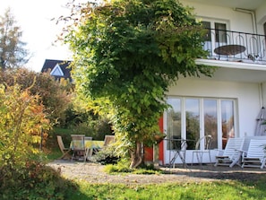 Ein Haus mit Garten, einem Esstisch mit Stühlen und einem Balkon mit Tisch und Stühlen.