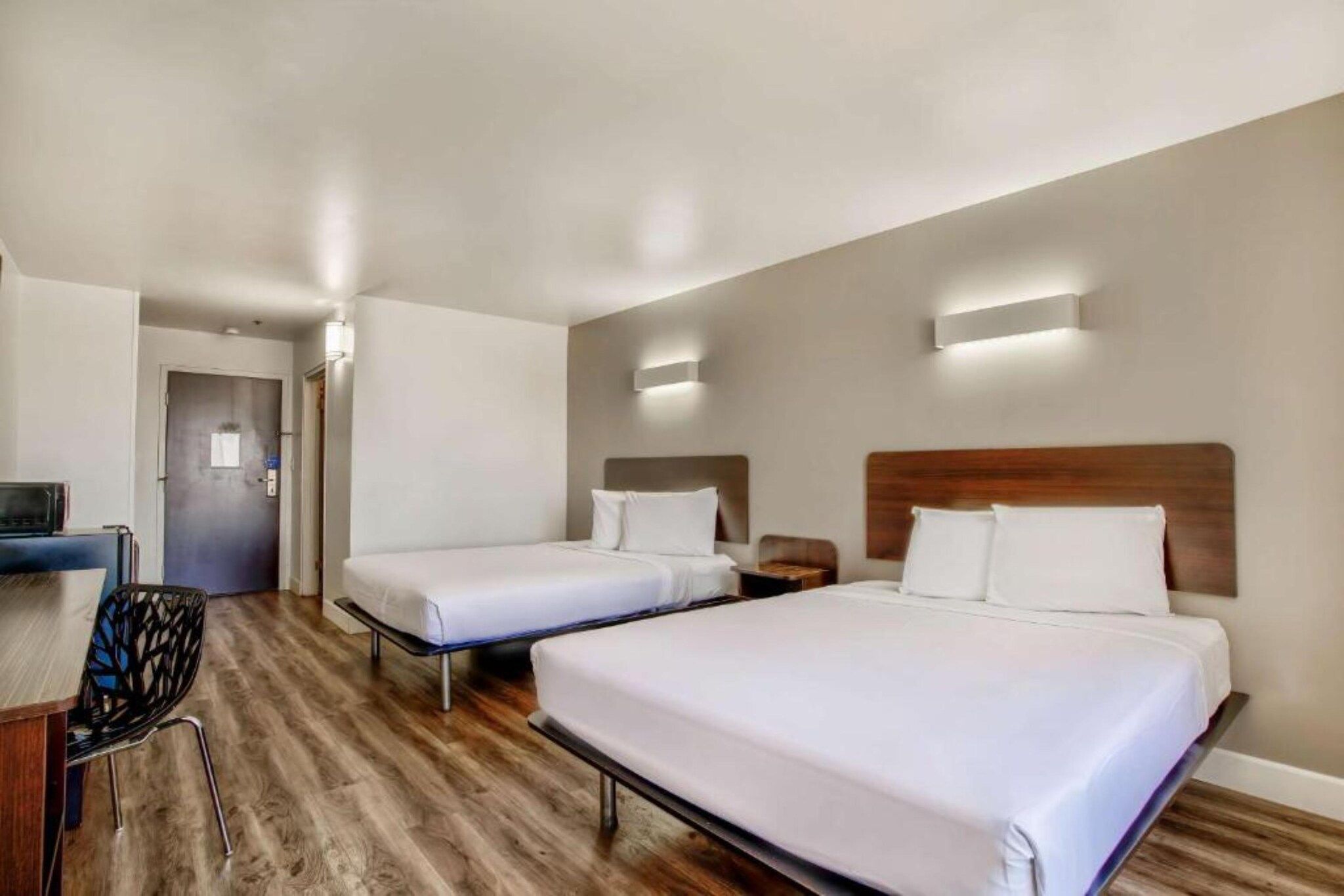 Ett hotellrum med två sängar, ett skrivbord och en stol.