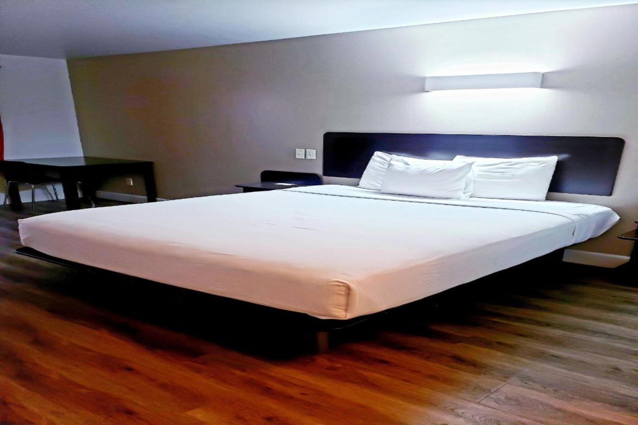 Habitación de hotel con una cama grande, una mesita de noche y una lámpara de pared.