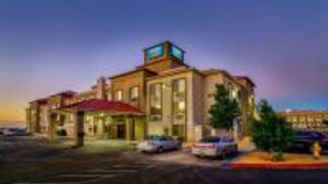 A hotel with a red roof, multiple windows, and a parking lot. - 1 Queen Bed | Non-Smoking (Hesperia)