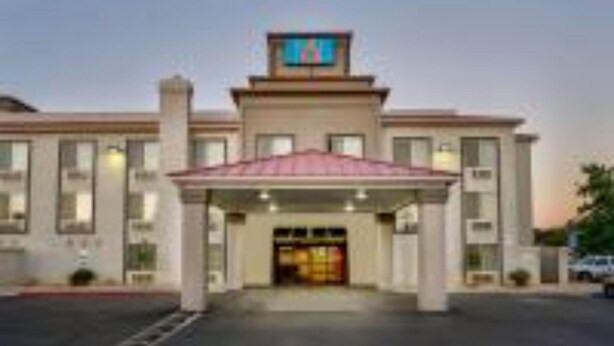 A hotel with a central entrance, a flat roof, and a sign above the entrance. - 1 Queen Bed | Non-Smoking (Hesperia)