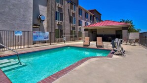 A swimming pool with a red roofed area, a metal fence, and a building with multiple windows. - 1 Queen Bed | Non-Smoking (Hesperia)