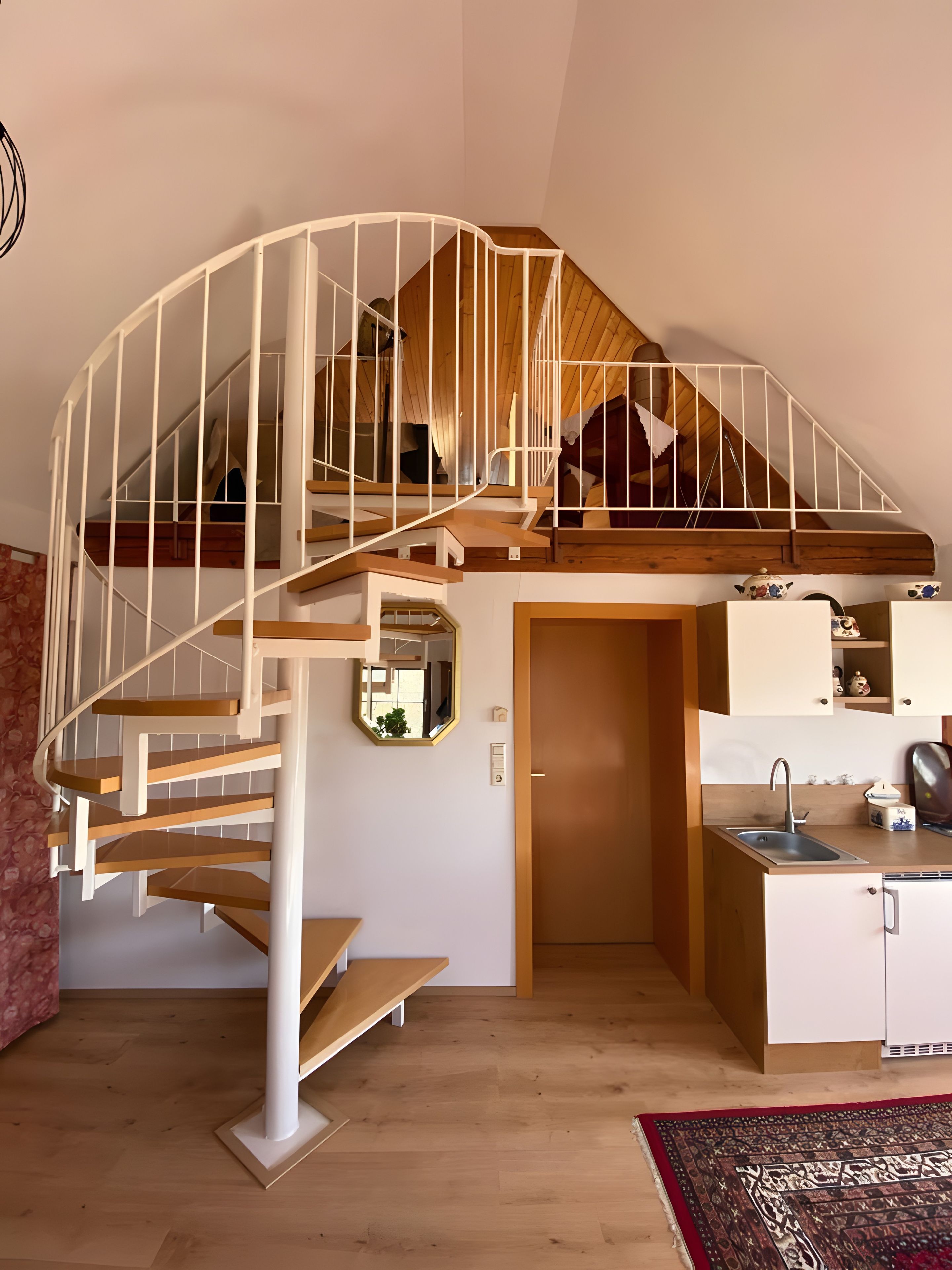 A modern interior with a spiral staircase, a kitchen area, and a small dining space.