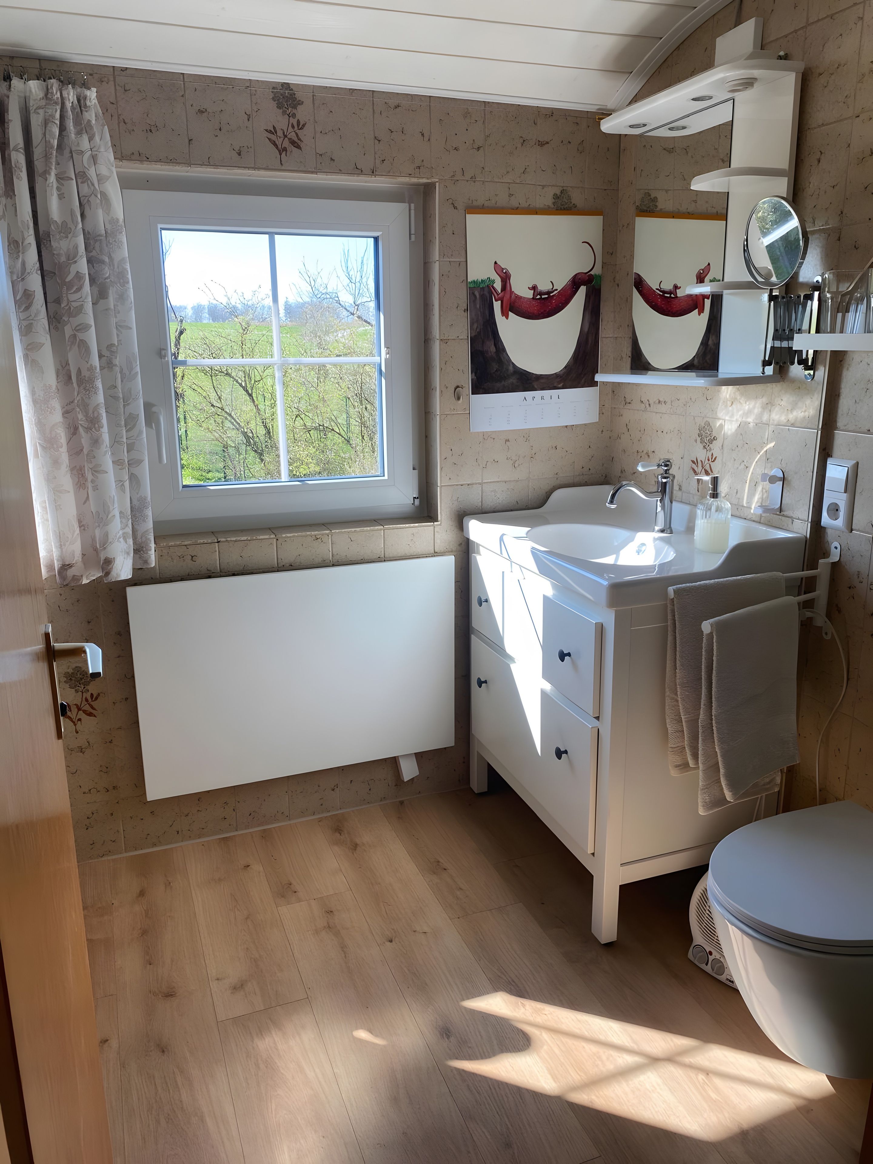 A bathroom with a window, a sink, a toilet, and a mirror.