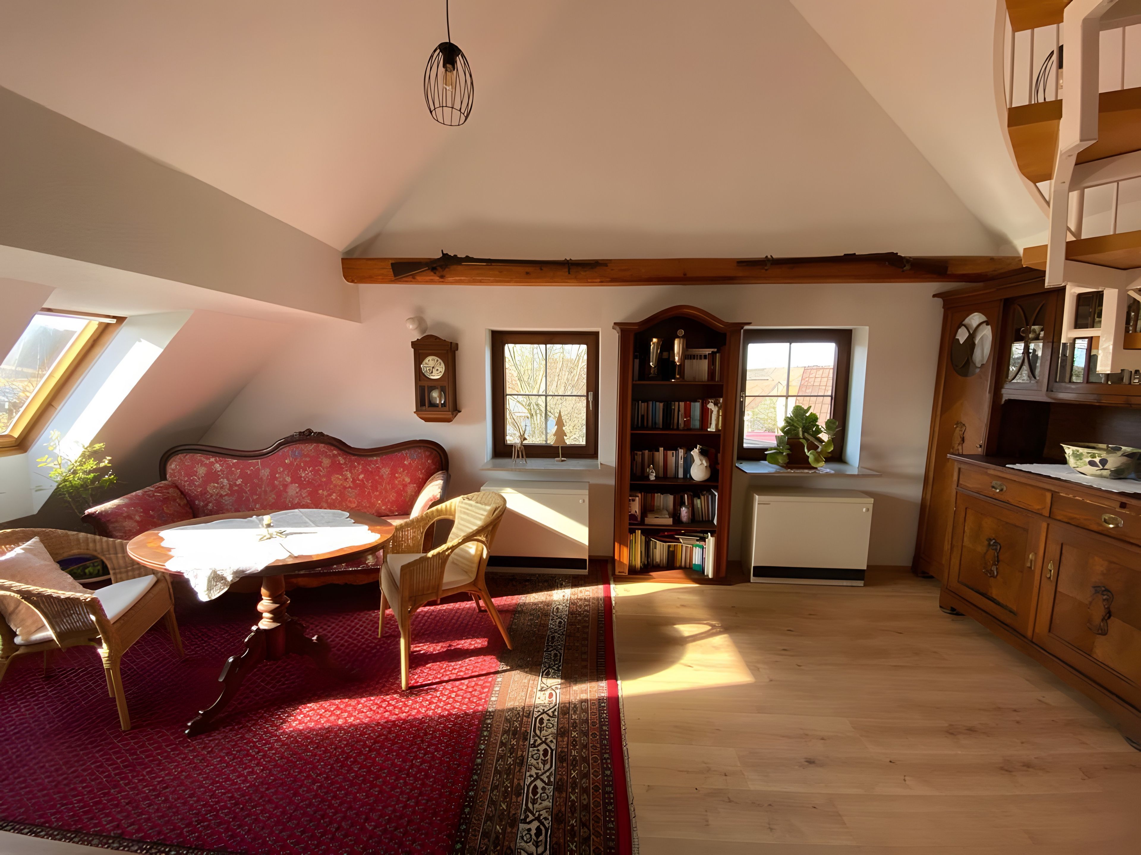 A cozy living room with a red sofa, a wooden coffee table, a bookshelf, and a dining area with a table and chairs.