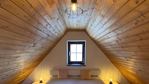 A bedroom with a sloped ceiling, a window, two bedside tables with lamps, and a bed with a white mattress. - Apartment 'Ferienwohnung in Upflamör' with Shared Garden, Balcony and Wi-Fi (Zwiefalten)