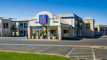 A motel with a prominent '6' sign, multiple rooms, and a parking lot.