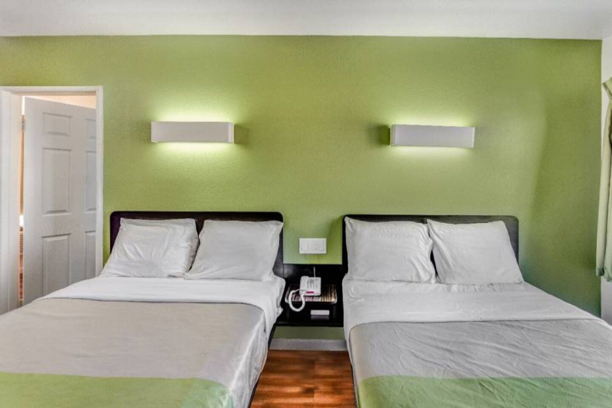 Ein Doppelzimmer mit zwei Betten, einem Nachttisch und einer Wandlampe.