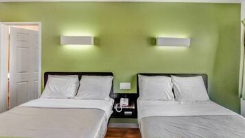 Ein Doppelzimmer mit zwei Betten, einem Nachttisch und einer Wandlampe.