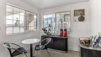A small room with a white table and two chairs, a coffee machine, and a sign on the wall.