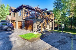 Ein zweistöckiges Holzhaus mit Garage, einer Treppe, die zu einem Balkon führt, und einem Auto auf der Auffahrt.