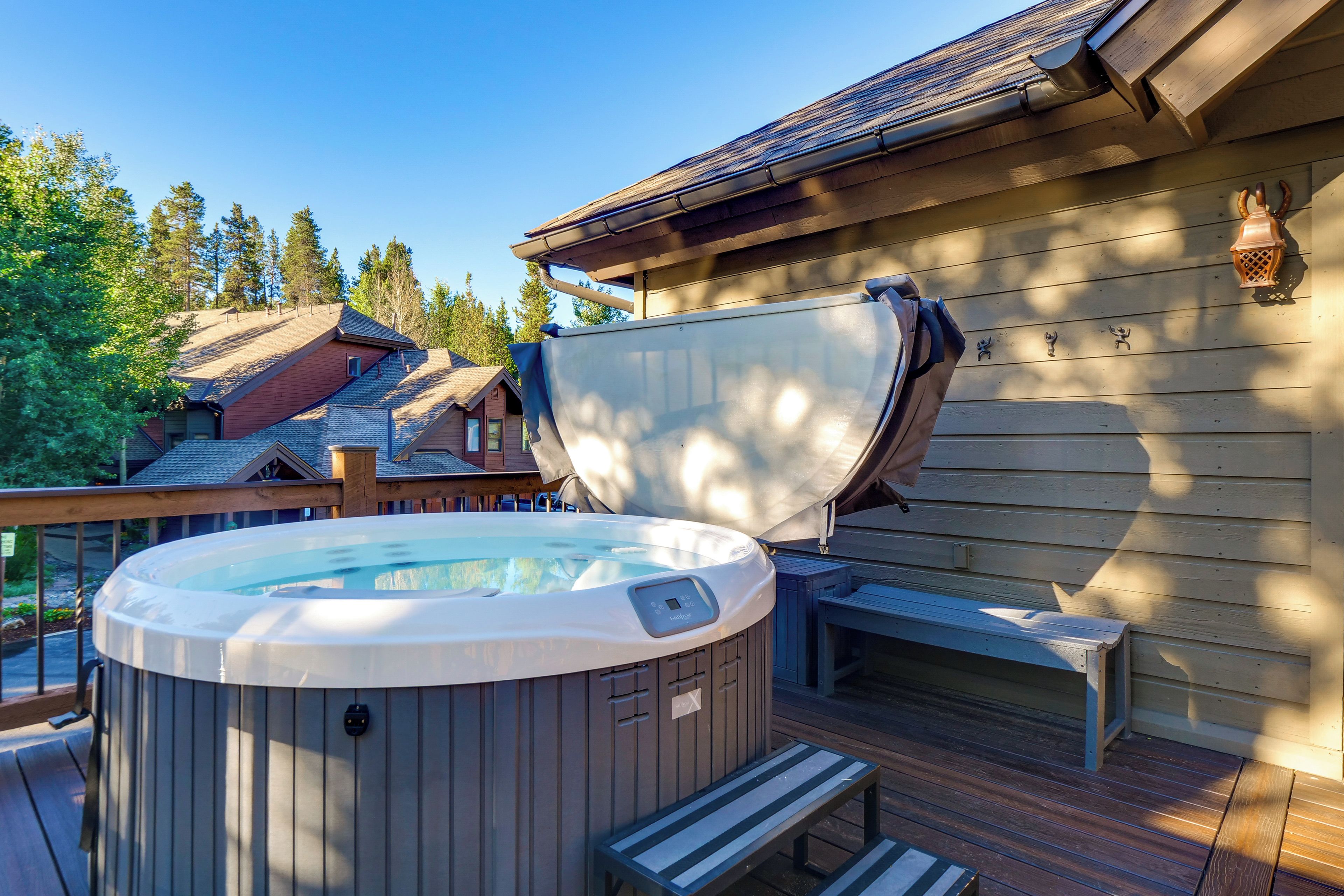 Un bain à remous sur une terrasse en bois, agrémentée d’un banc, entouré d’un chalet en bois doté d’un toit en pente.
