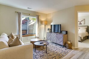A living room with a sofa, a coffee table, a television on a cabinet, and a lamp. - Steps to Dtwn & Peak 9 Lifts! Hot Tub Hideaway (Breckenridge)