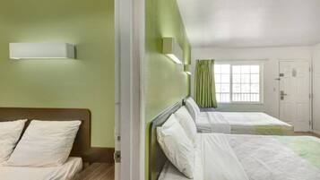 Ein Hotelzimmer mit zwei Betten, einem Fenster mit Vorhängen und einer Tür.