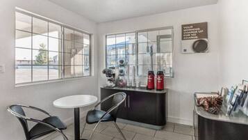 A small room with a white table and two chairs, a coffee machine, and a sign on the wall.