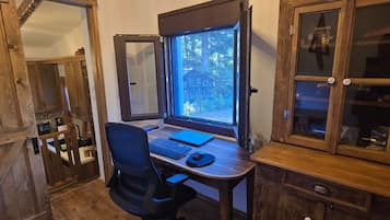 Una stanza con rivestimenti in legno, una scrivania, una sedia e una finestra con vista su una foresta.