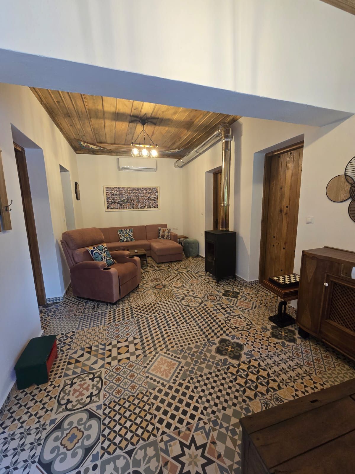 A living room with a patterned floor, a brown sofa, a wooden cabinet, and a fireplace.