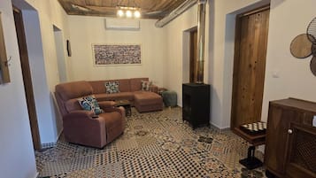 A living room with a patterned floor, a brown sofa, a wooden cabinet, and a fireplace.