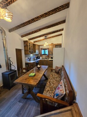 A cozy interior with a wooden dining table, bench seating, a kitchen area, and a visible chimney.