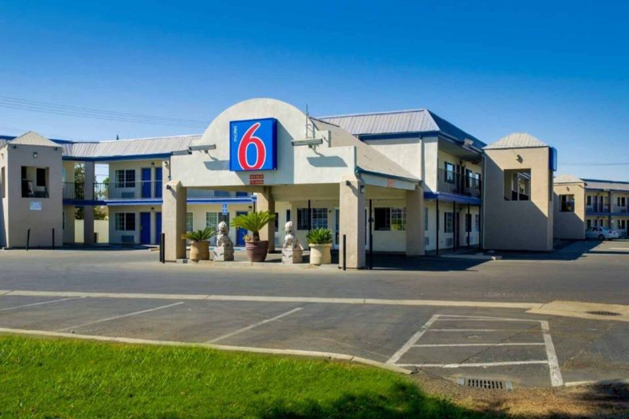 A motel with a prominent '6' sign, multiple rooms, and a parking lot.