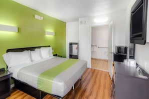 Quarto de hotel com cama, mesas de cabeceira, televisão e banheiro visível por uma porta aberta.