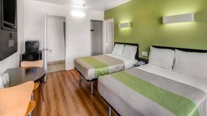 Ein Hotelzimmer mit zwei Betten, einem kleinen Tisch und einem Fernseher.