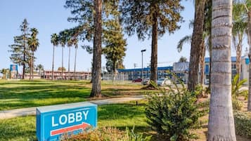 A sign labeled 'LOBBY' in a grassy area with trees and a building in the background.