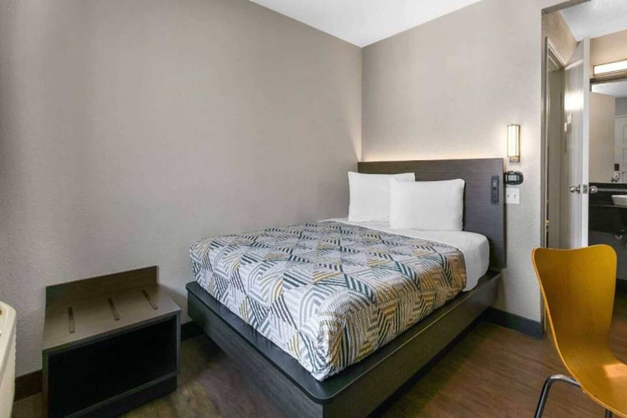 A hotel room with a bed, a chair, and a small table.