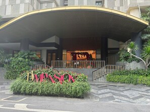 A hotel entrance with a curved canopy, a staircase, and a sign with the hotel's name. - Spacious 3BR Family Stay in Dist 1 _ Pool, Gym & Balcony (Thành phố Hồ Chí Minh)