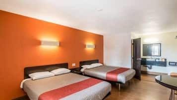 Ein Hotelzimmer mit zwei Betten, einem kleinen Tisch und einem durchgegangenen Badezimmereingang.
