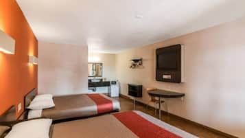 Habitación de hotel con dos camas, una kitchenette pequeña, un televisor y un escritorio.