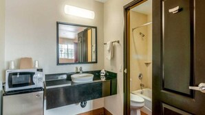 A bathroom with a sink, mirror, toilet, shower, and a microwave. - 1 King Bed | Non-Smoking, Micfridge (Bell Gardens)
