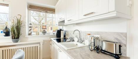 A modern kitchen with white cabinetry, a built-in oven, a coffee maker, and a toaster.